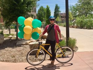 Happy bicyclist standing with balloons