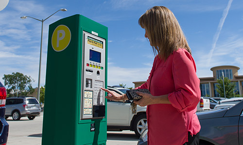 Photograph of woman paying for parking at a "Pay-to-Park" station in the Morgan Library lot.