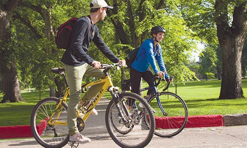 Photograph of two students riding their bicycles around " The Oval".