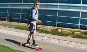 Photograph of a student riding longboard on the bike path that runs just south of the CSU Rec Center.