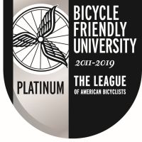 A logo that is black, silver and white, and reads the following: "Platinum", "Bicycle Friendly University", "2011-2019", "The League of American Bicyclists". It also has an image of a bicycle wheel with wings on it.